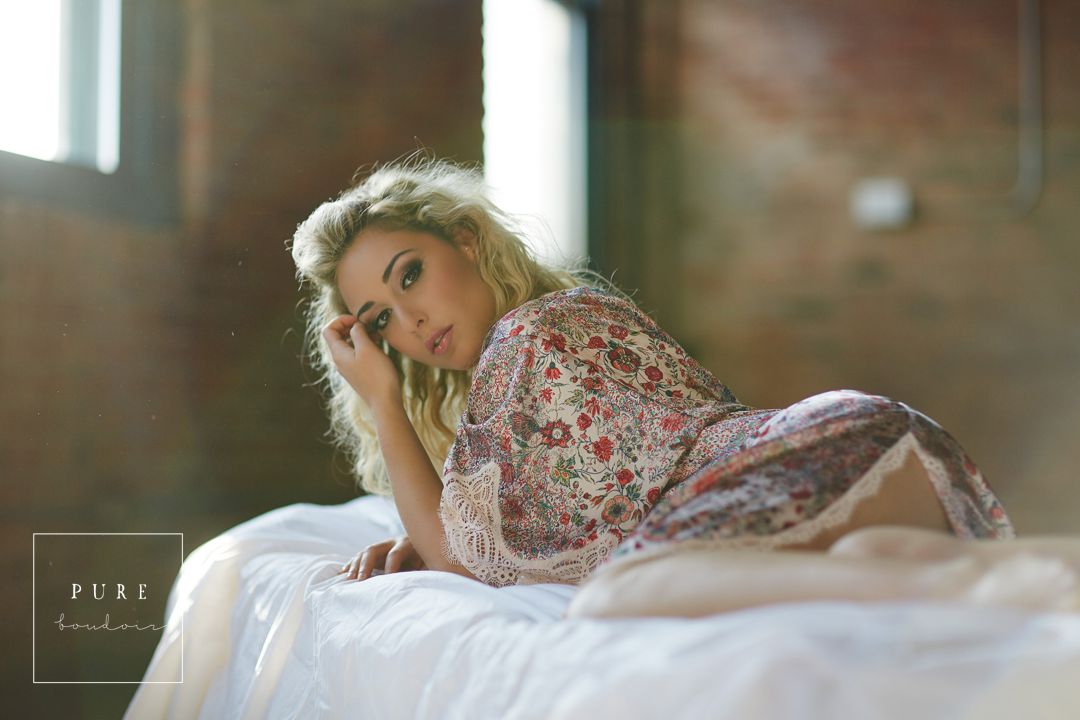 woman in floral print lingerie on bed looking at camera chicago boudoir