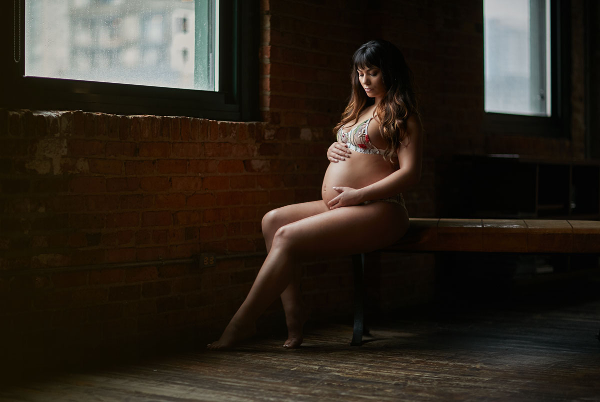 pregnant woman sitting next to window maternity boudoir