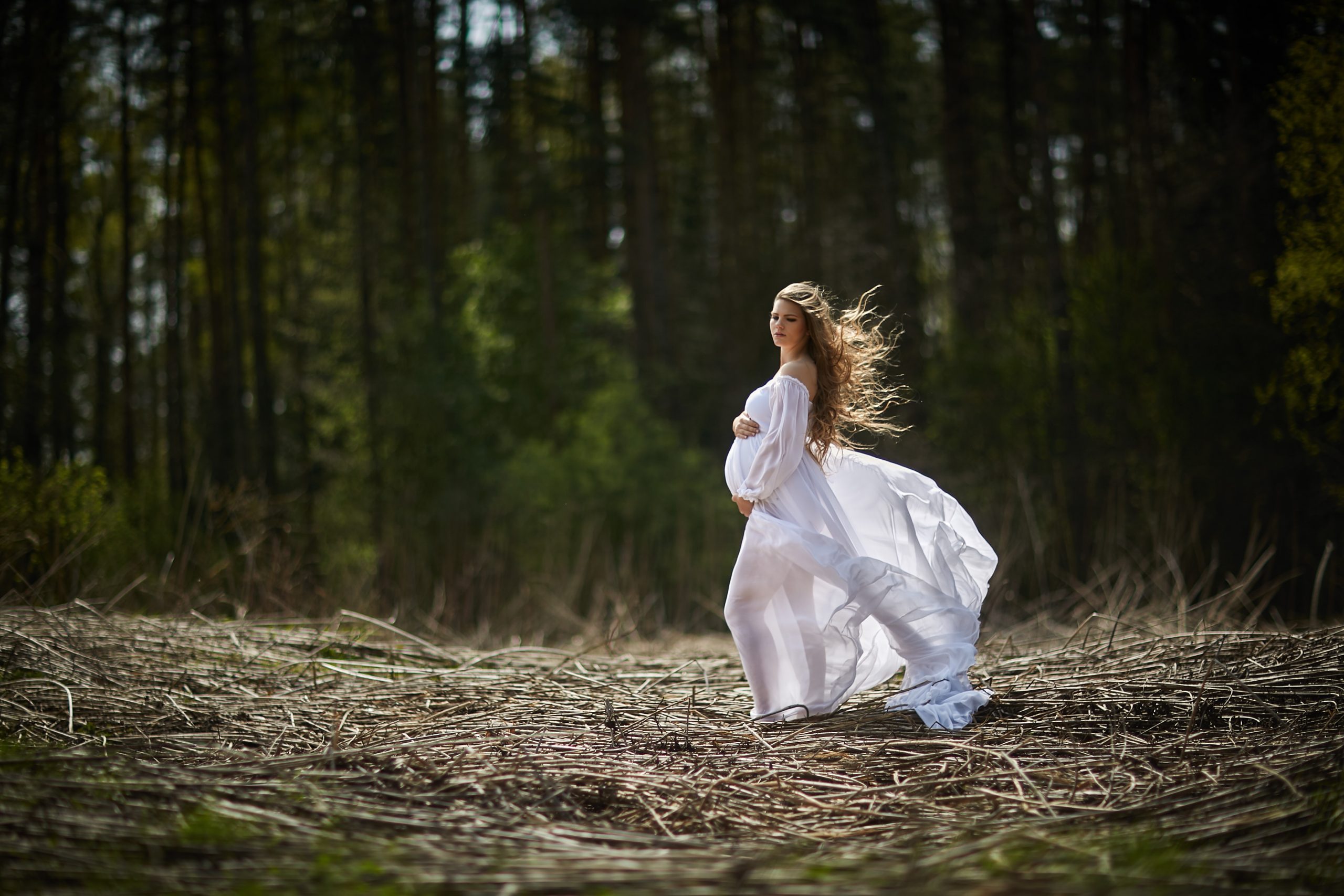 woman in white dress in woods pregnant