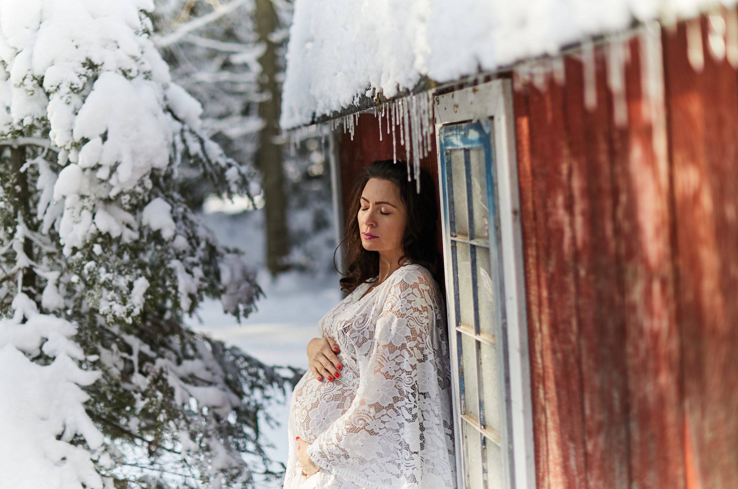 woman leaning on house winter maternity boudoir